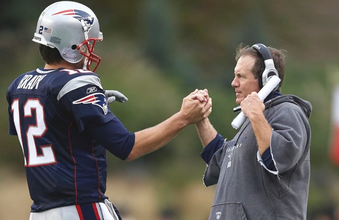 Bill Belichick clasps hands with Tom Brady.